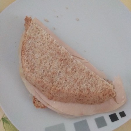 Ein Schinkensandwich auf einem weißen Teller.